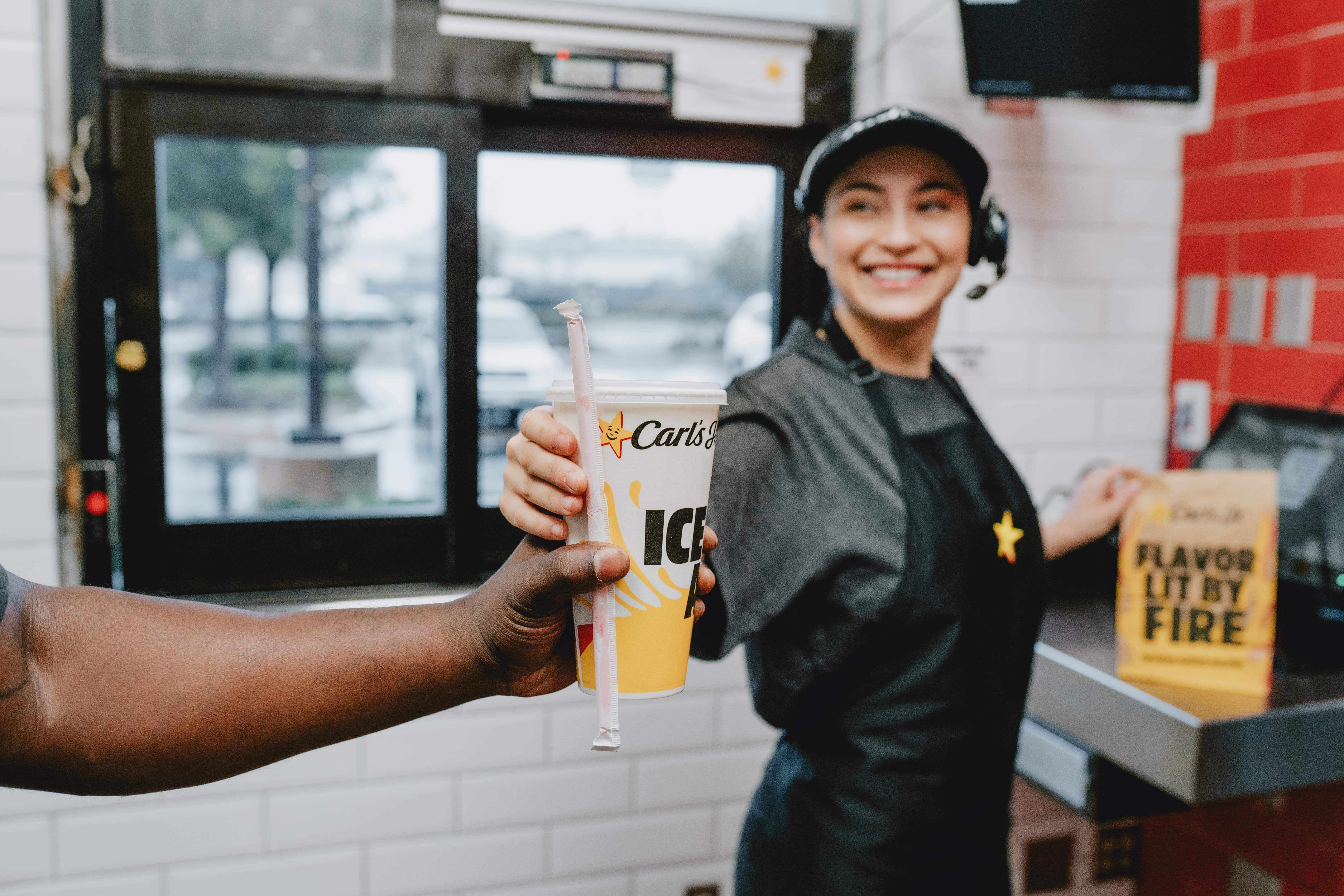 Hardees employee at the counter handing out the order to a customer
