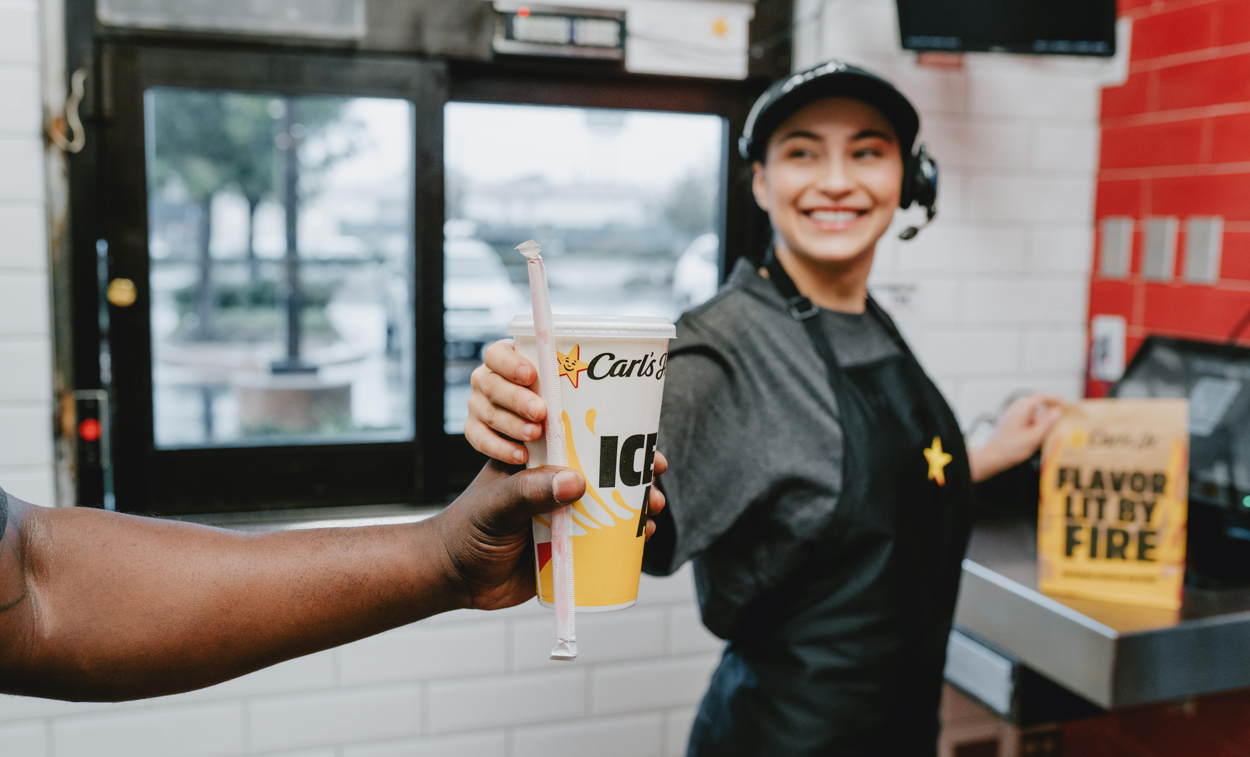 Hardees employee at the counter handing out the order to a customer